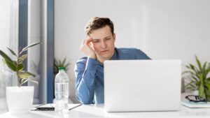 Uomo perplesso davanti al computer mentre cerca di riprendere in mano la comunicazione digitale dopo le vacanze